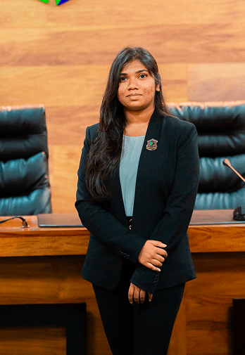 Duvini in a dark blazer seated at a wooden desk