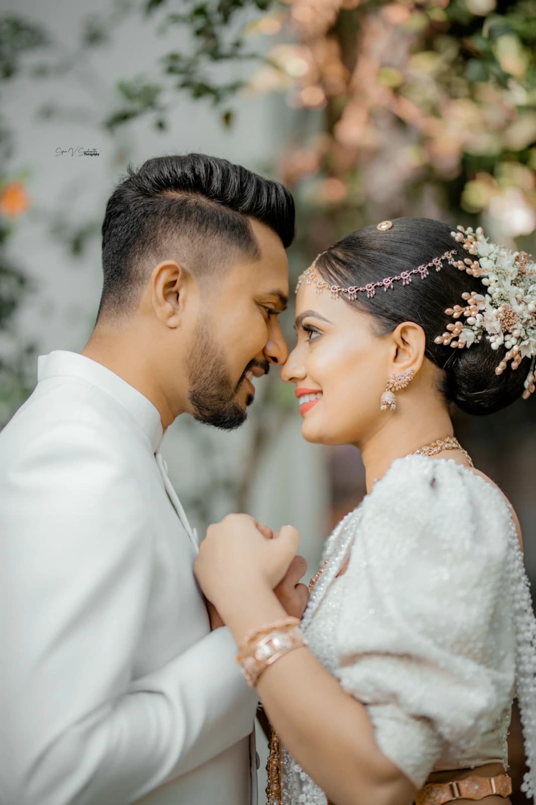 Couple sharing a quiet moment, foreheads touching, in traditional wedding attire