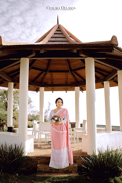 Bride in a pink sari standing in a white-columned pavilion